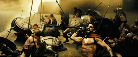 Leonidas, seen in front of felled and falling Spartans draws back his spear and shouts.