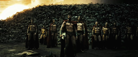The Spartans look forward from before a pile of their slain enemies, which looms over them.