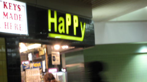 A blurry shot of a sign over a news stall at Reading Terminal, which reads HaPPy. The two capital Ps are clearly from another set of letters.