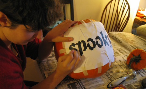 Alisa punches the outline of her design into the pumpkin skin through a printout taped to the front. 