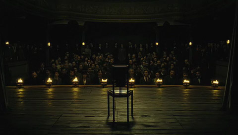 Eisenheim's chair sits empty, facing the audience, in the fire-lit theatre as the curtains open.