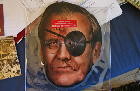 Die-cut record in the shape of a horribly ugly, eye-patched Donald Rumsfeld head.