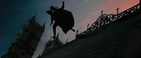 V caught in mid-air as he leaps across a church rooftop at sunset.