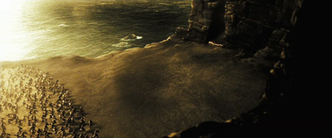 The Spartans arrange themselves in a tight group between two cliff walls, as the Persians rush towards them across an open seaside cliff range.