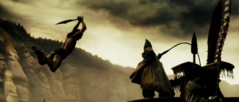 Stelios leaps through the air, sword above his head, towards a Persian emissary whose whip is drawn back.