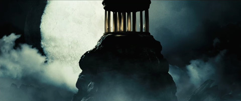 A cupola atop a mountain peak in front of a full moon.