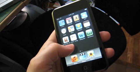 My iPod Touch in my hand, held above a black office chair.