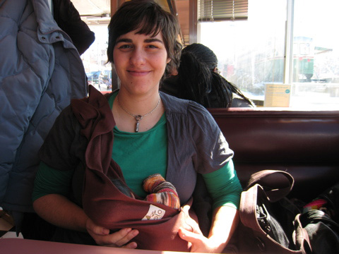 Alisa, sitting across from me in the booth at a diner, smiling with Blackbird in the sling, her arm poking out.