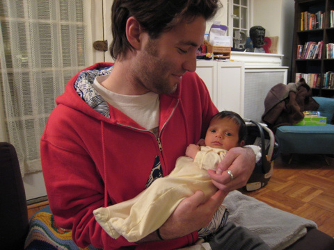 Blackbird in her yellow PJs, being held by her uncle Larry in our living room.