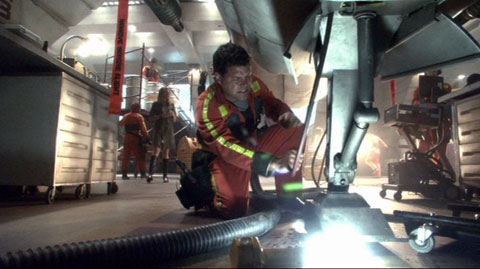 Chief Tyrol angrily pulls at a hose on a Viper's front landing foot.
