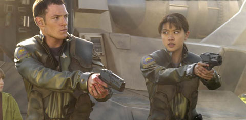 Boomer and Helo raise their sidearms in front of their ship.