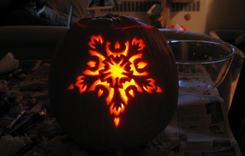 My pumpkin, lit up, with an ornate pentragram-eqsue design.