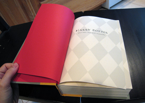 The title page of the book, which has faint grey a diamond pattern covering the page, sits in a spread with a vibrant red sheet that also serves as the inside covers.