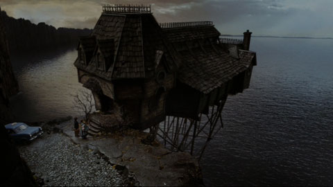 A rickety old house stands just off a cliffside on spindly wood scaffolding.