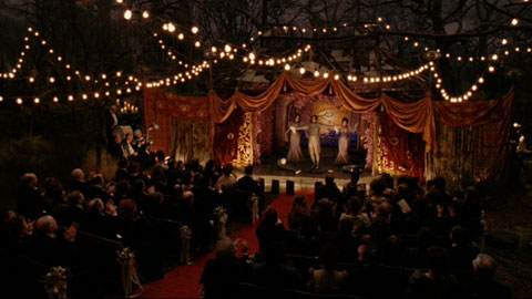 Players in Olaf's play, with the audience looking on and strung lights above them.