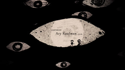 On a black screen, the children run through a large eye-shaped form, surrounded by five smaller eyes, randomly placed, with black irises and white pupils.