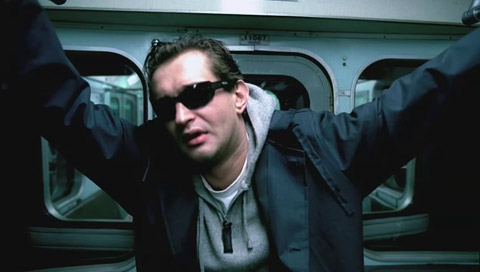 Anton, not looking so good and with sunglasses on, holds himself up with both arms while riding the subway.