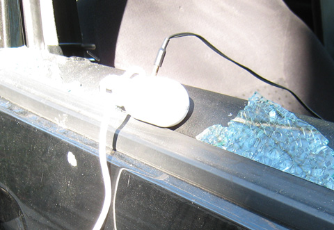 My white iPod charger sits on the sill of my car's broken window, still connected to the tape adapter.